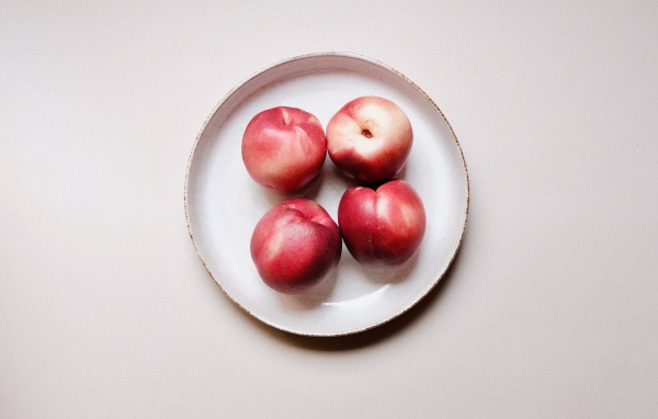 Четыре красных спелых нектарина на тарелке 