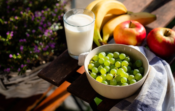 Зеленый виноград на столе с бананами, яблоками и молоком
