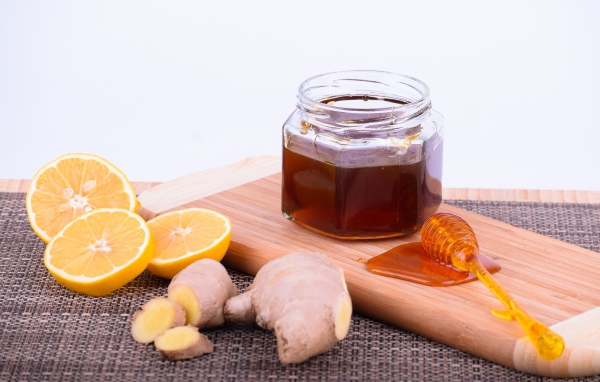 Банка меда на доске с лимоном и корнем имбиря 