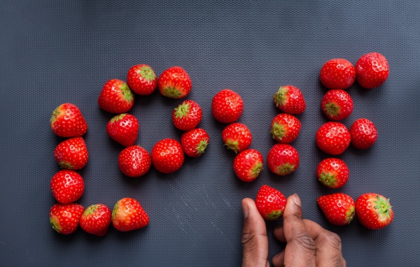 Надпись LOVE выложена из ягод спелой клубники 