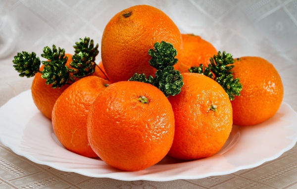 Many orange tangerines on a plate with cones