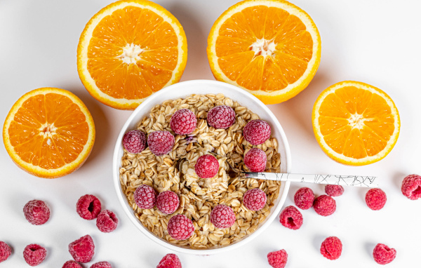 Овсяные хлопья с малиной на белом фоне с апельсинами