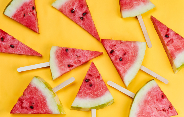 Кусочки арбуза на палочках на желтом фоне