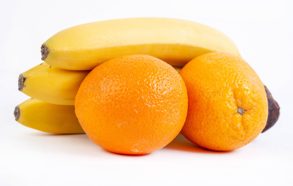 Спелые апельсины и бананы на белом фоне 