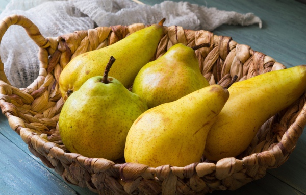 Спелые груши лежат в корзине на столе