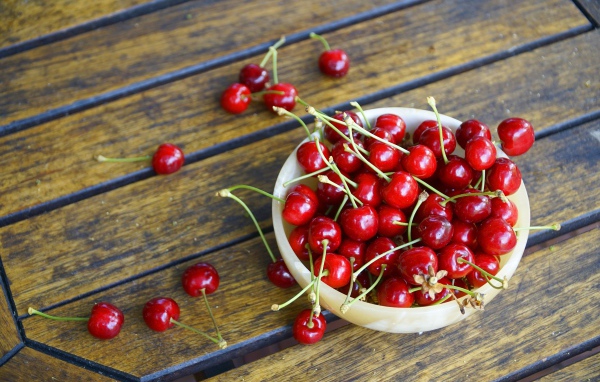 Спелые красные вишни в тарелке на столе 