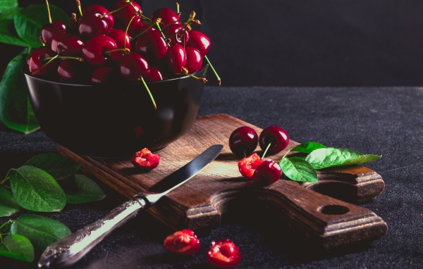 Спелые красные черешни на разделочной доске на столе 
