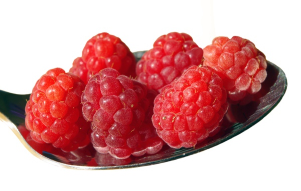 Спелая красная малина в ложке на белом фоне 