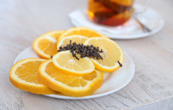 Нарезанный апельсин и лимон на тарелке с гвоздикой