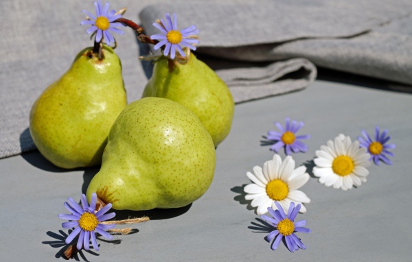 Три груши на столе с цветами
