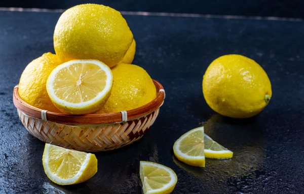 Мокрый лимон с кусочками на черном столе 