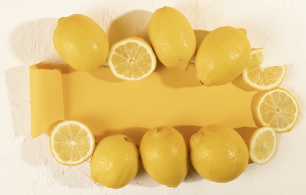 Желтые лимоны на белом фоне с листом бумаги