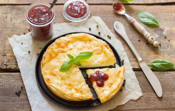 Cheese pie on the table with ketchup and basil