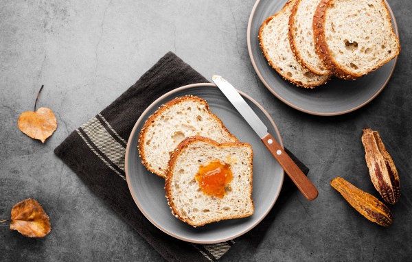 Куски хлеба с джемом на сером столе 