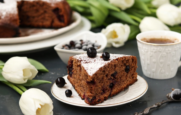 Кусок пирога со смородиной на столе с тюльпанами 