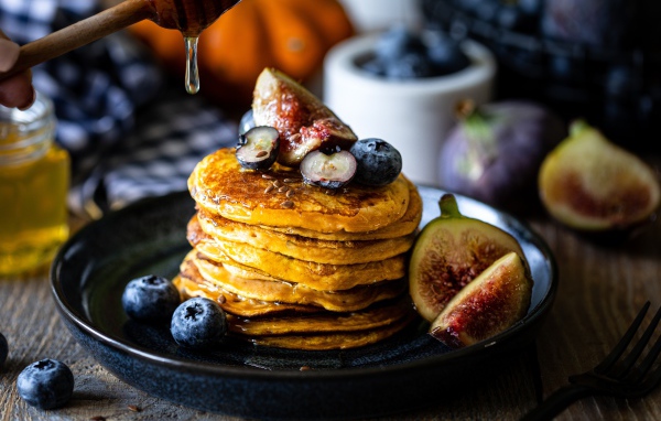 Аппетитные оладьи на тарелке с ягодами черники и инжиром