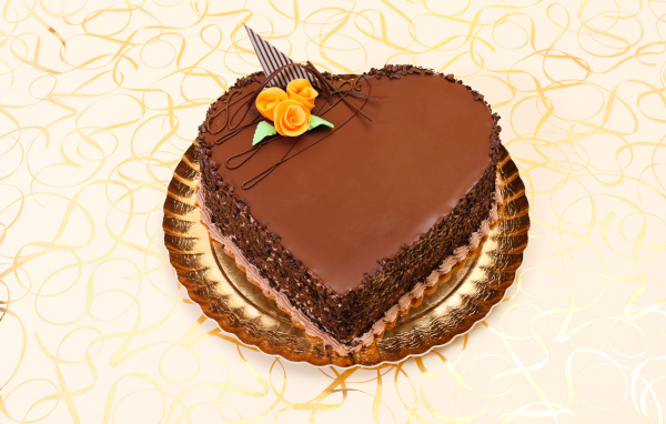 Красивый торт в форме сердца в шоколаде на столе