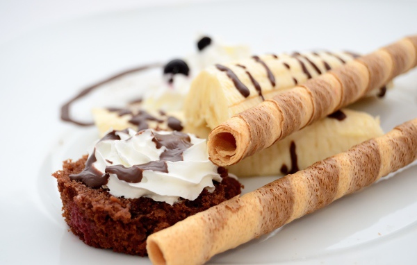 Пирожное на тарелке с бананом и сладкими трубочками