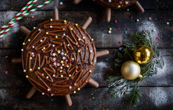 Шоколадное пирожное на столе с еловыми игрушками 