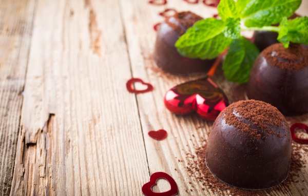 Шоколадные конфеты с какао на столе с мятой и сердечками