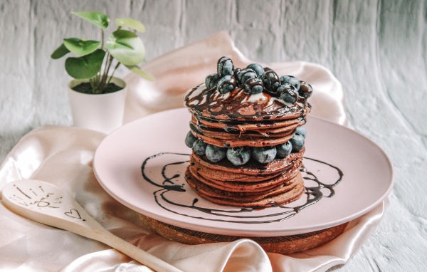 Шоколадные оладьи с ягодами черники на белой тарелке