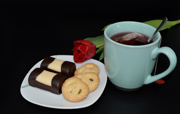 Печенье с конфетами на столе с чашкой чая и тюльпаном