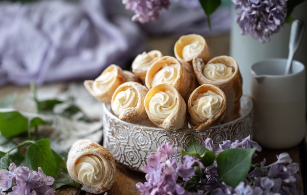 Трубочки с кремом на столе с цветами сирени