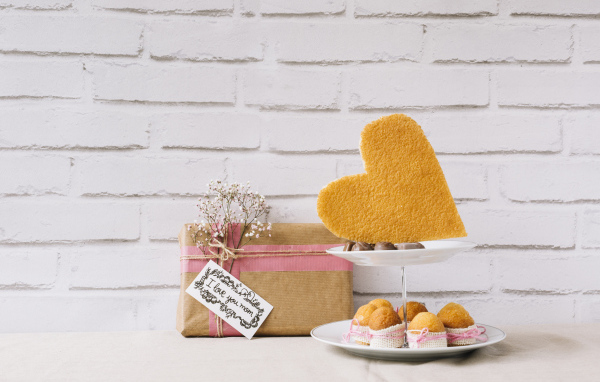 Кексы на тарелке на столе с подарком для любимой 