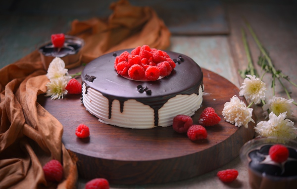Вкусный торт с шоколадом и малиной на столе с цветами хризантемы 