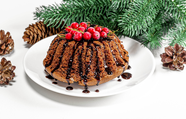 Вкусный кекс с шоколадом и красной смородиной на столе с еловой веткой и шишками