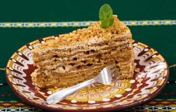 Вкусный медовый торт с орехами на красивой тарелке 