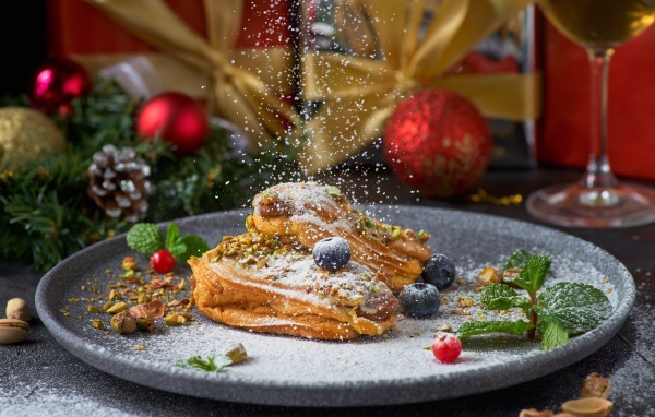 Вкусные сладкие эклеры с сахарной пудрой на блюде с ягодами 