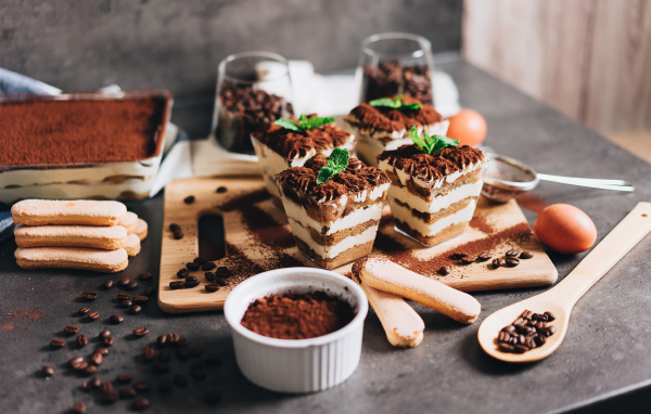 Аппетитный десерт тирамису в креманках на столе с кофейными зернами