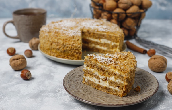 Торт медовик на столе с орехами и чашкой кофе