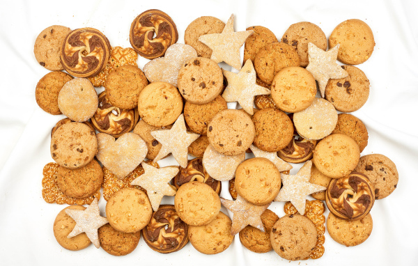 Много песочного печенья разной формы на белом фоне