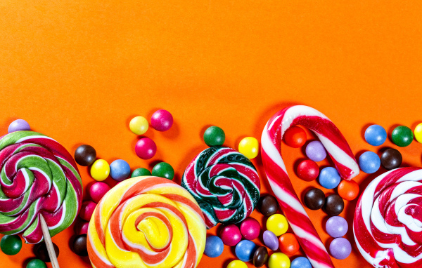Разноцветные конфеты на оранжевом фоне