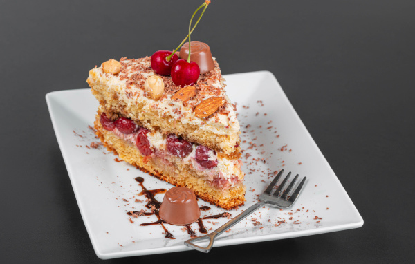 Кусок торта с ягодами вишни и миндальным орехом