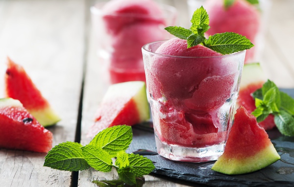 Фруктовое мороженое в стакане на столе с кусочками арбуза и мятой