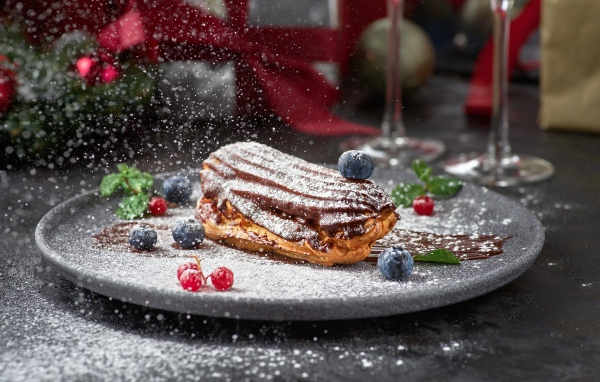 Вкусное пирожное на тарелке с сахарной пудрой и ягодами