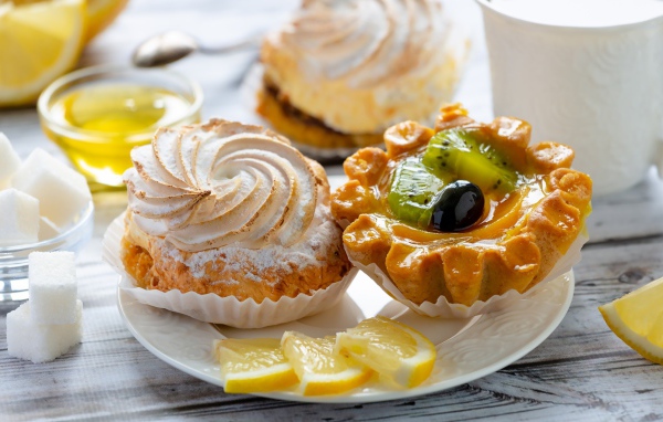 Вкусные аппетитные пирожные на тарелке с лимоном