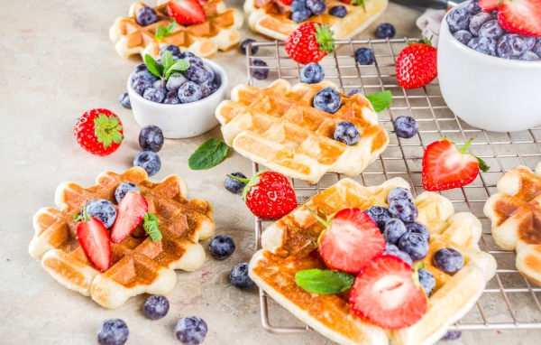 Вкусные сладкие вафли на столе с ягодами черники и клубники