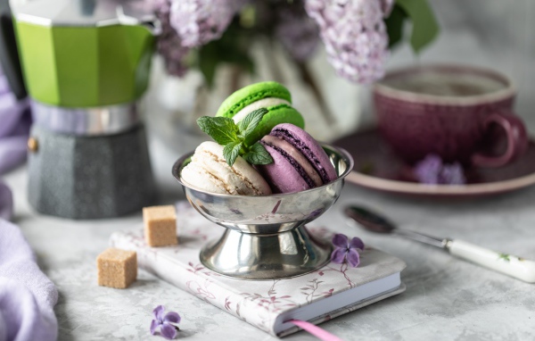 Три печенья макарун на столе с блокнотом