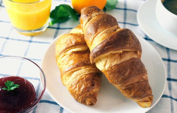 Два круассана на столе с джемом и соком