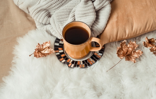 Чашка кофе стоит на покрывале с теплым свитером 