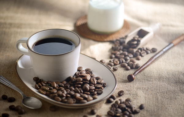 Чашка крепкого кофе на столе с зернами