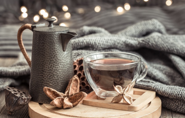 Чашка чая на столе с чайником и теплым пледом