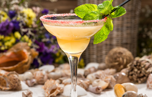 Коктейль с мятой в бокале на столе с ракушками 