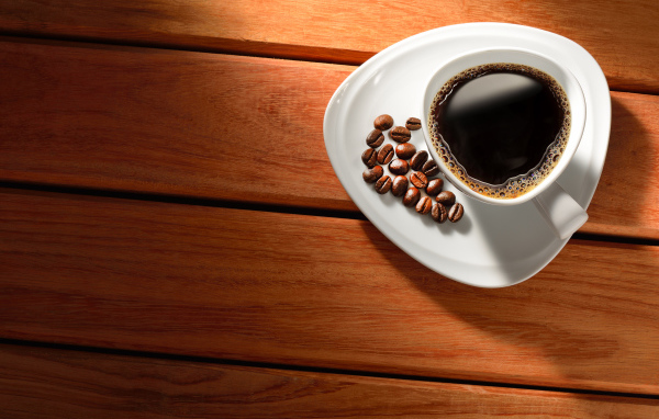 Чашка кофе на тарелке с зернами на деревянном столе