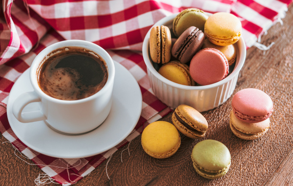 Чашка кофе на столе с десертом макарун 