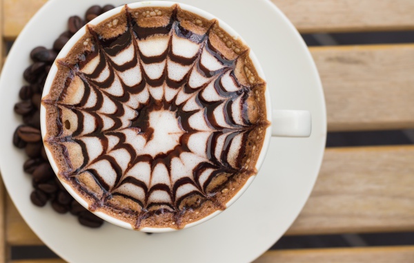 Чашка кофе с рисунком на пене на столе